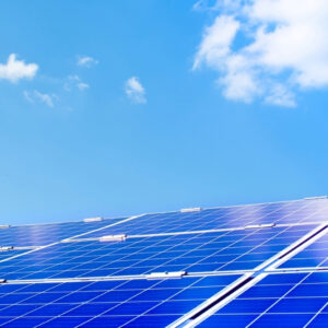 Primo piano di un pannello fotovoltaico installato su un tetto sotto un cielo estivo azzurro, con qualche nuvola