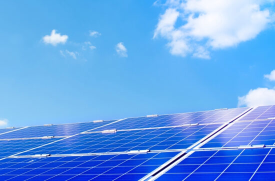 Primo piano di un pannello fotovoltaico installato su un tetto sotto un cielo estivo azzurro, con qualche nuvola